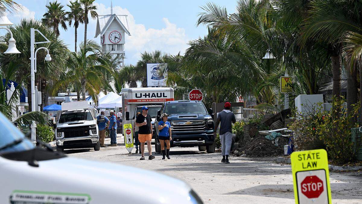 Work trucks and people along Bridge Street in Bradenton Beach after Hurricane Helene on Oct. 2, 2024.