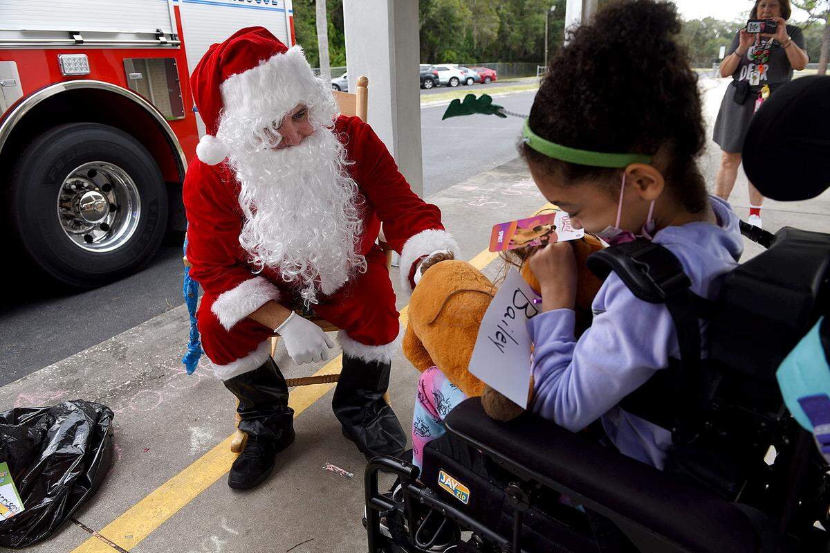 12/20/21—Santa talks with Bailey Yoder after giving her a stuffed toy. Santa arrived on an East Manatee Fire Rescue truck to delight of pre-kindergarteners and ESE students at Bashaw Elementary School.