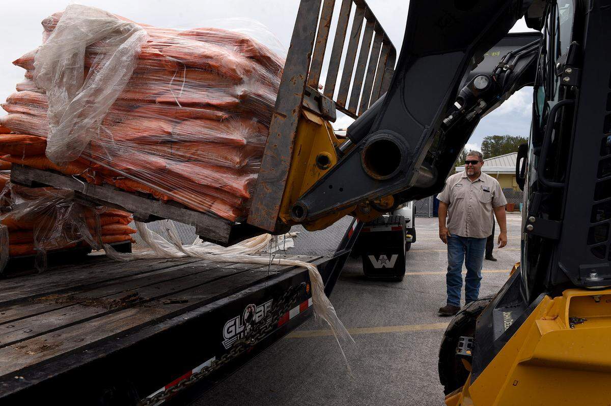 A Manatee County worker guides a pallet of sandbags at the Manatee County Public Beach where people can help themselves to up to 10 sand bags. Rain bands from a tropical disturbance impacting South Florida had not made their way to Manatee County beaches mid-morning Friday. The National Hurricane Center is forecasting the system to slightly strengthen into a tropical storm.