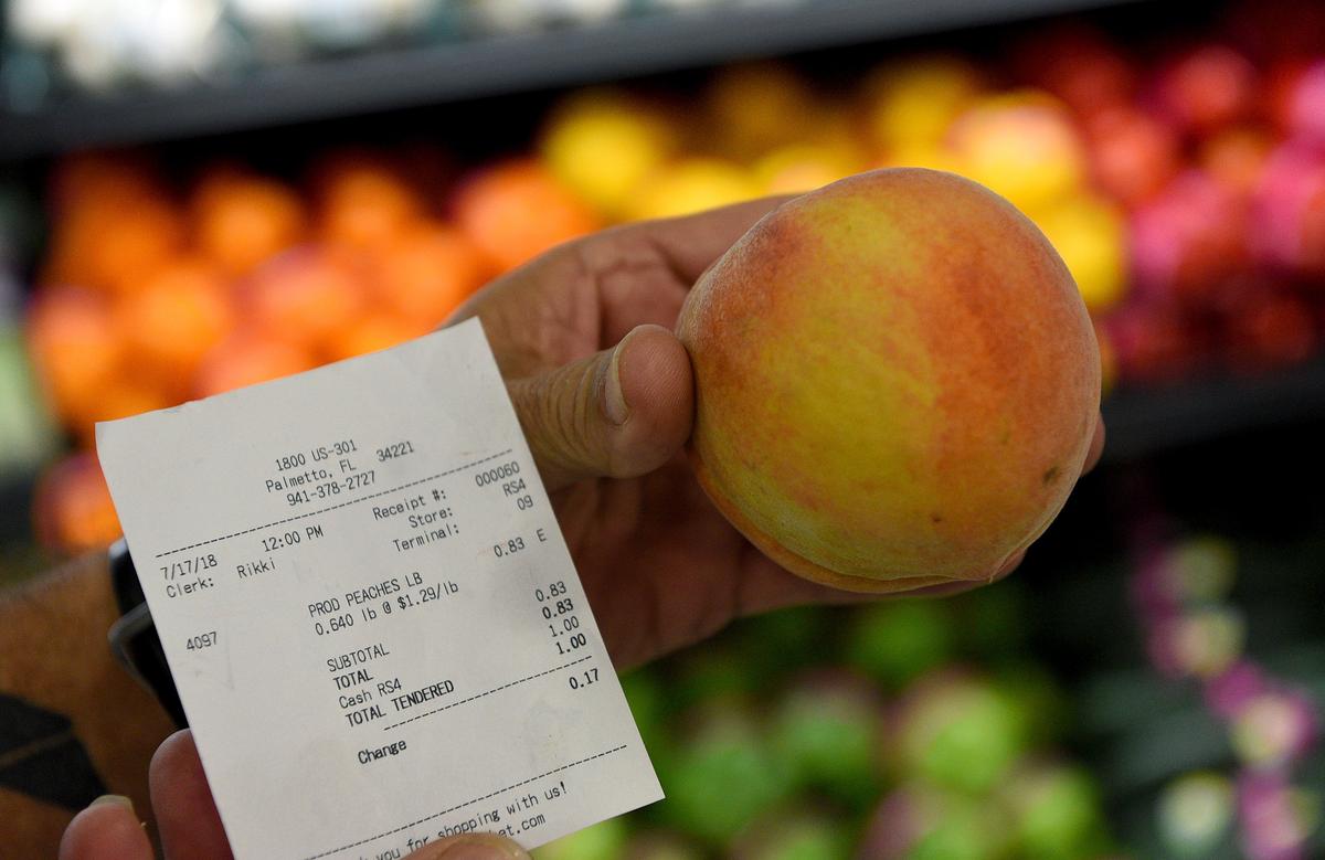 David Livingston holds the first peach sold at the new Detwiler’s Farm Market in Palmetto.