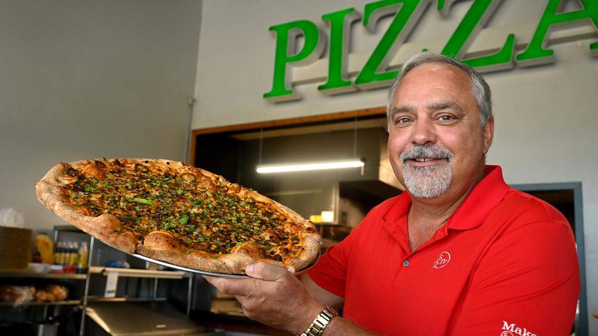 Todd Surdez, who owns Gianni’s Pizza Express with his wife Maia, holds up a fresh pie. The storefront opened recently at 4927 96th Street E., Palmetto.