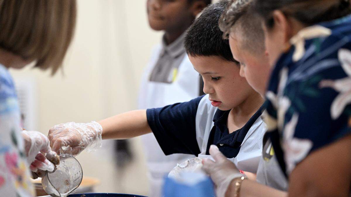 Students check a recipe while they make apple pies for their families’ Thanksgiving celebrations at Visible Men Academy on Friday, Nov. 17, 2023.
