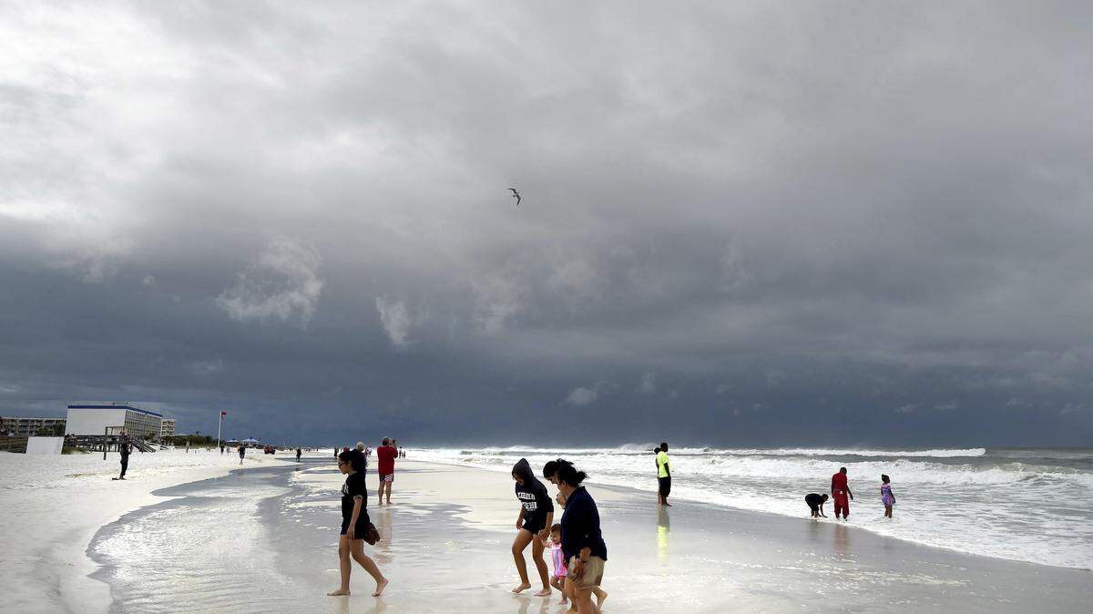 Beachgoers walk on Okaloosa Island in Fort Walton Beach on Monday as Subtropical Storm Alberto approached the Gulf Coast. The storm's gusty rain and brisk winds roiled the seas, keeping white sandy beaches emptied of their usual Memorial Day crowds.