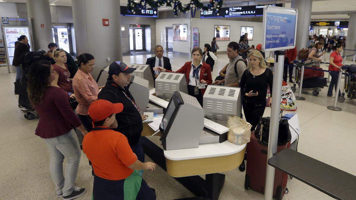 FILE - In this Nov. 25, 2015 file photo, travelers check in their luggage as they prepare to travel at Miami International Airport in Miami. A stronger economy and lower gas prices means Thanksgiving travelers can expect more highway congestions in 2015. Airlines for America, the lobbying group for several major airlines, forecasts 25.3 million passengers will fly on U.S. airlines, up 3 percent from last year.(AP Photo/Alan Diaz)