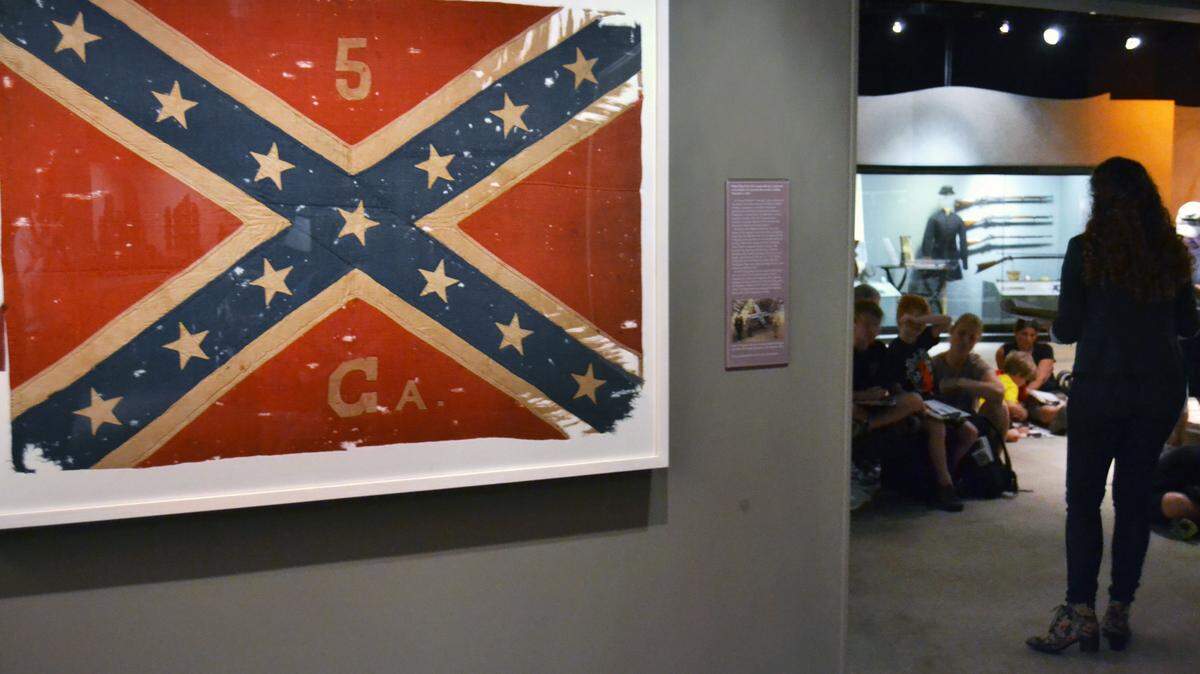 In this July 19, 2014 photo, a guide at the Atlanta History Center leads visitors through an exhibit of Civil War items in Atlanta. The items include the 5th Georgiaís battle flag that was captured by Pvt. L.C. Young of the 56th New York Regiment during fighting along Gen. William T. Shermanís March to the Sea in November 1864. Young returned it in 1884. (AP Photo/Christopher Sullivan)