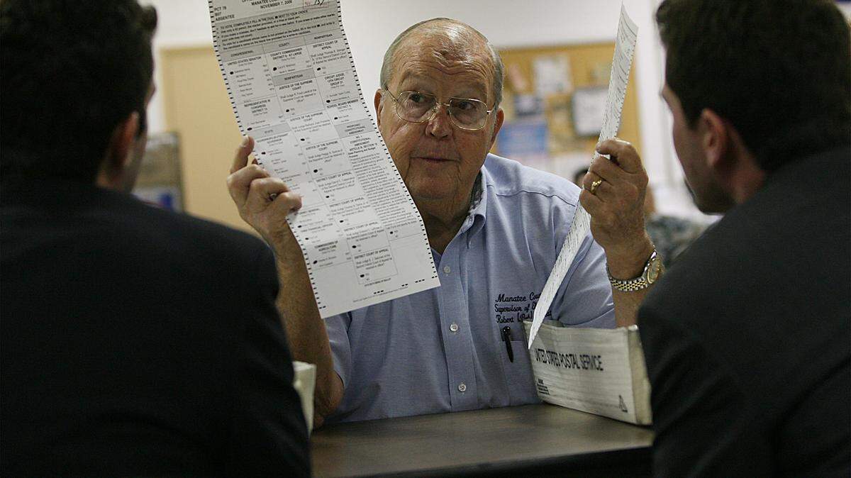 Manatee County Supervisor of Elections Bob Sweat shows an original and a duplicate ballot to attorneys Jim Delgado, left, of Christine Jennings’ campaign and Glen Burhans, of Vern Buchanan’s campaign, both candidates in the District-13 congressional race, during a manual recount of Manatee County ballots in this file photo.