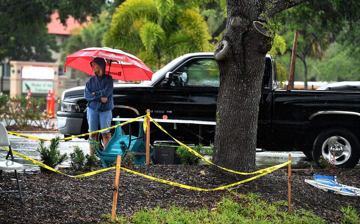 A woman with an umbrella stands near prime parade watching territory on 39th Street West after the 2022 De Soto Grand Parade was cancelled because of bad weather.