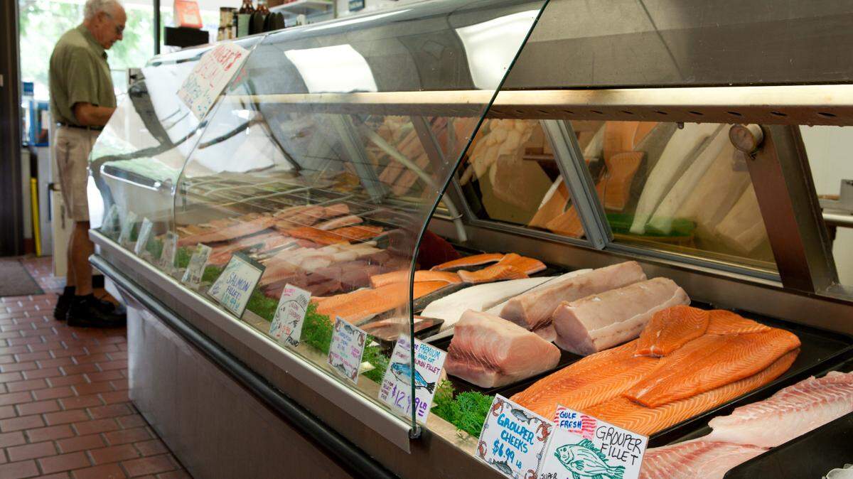Grouper and assorted seafood fillets on display at a store in case.