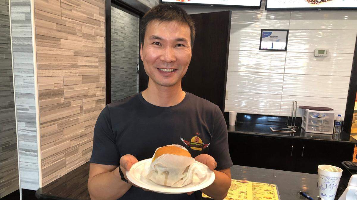 Kevin Li offers one of the cheeseburgers, made from certified fresh Angus beef, and served at his new business, R Burgers N’ Wings, 4266 53rd Ave. E., Bradenton.