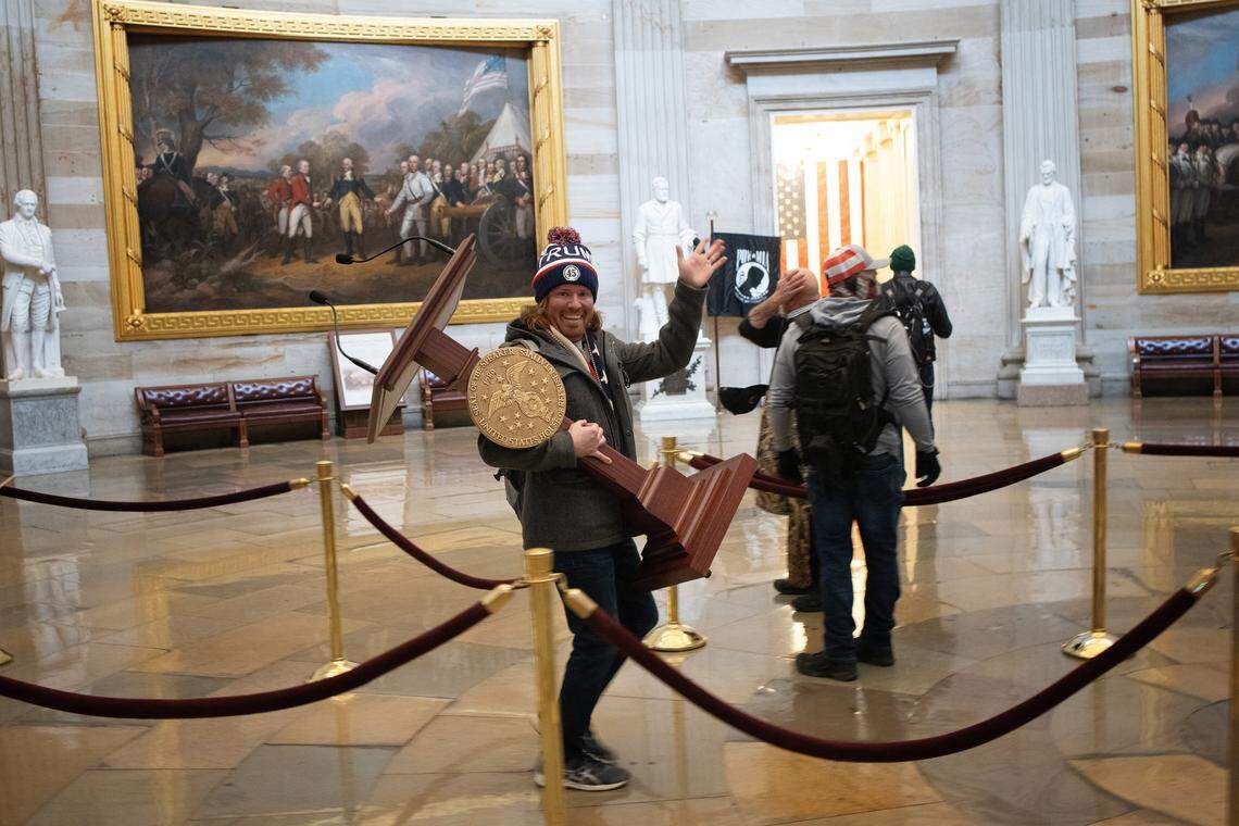 WASHINGTON, DC - JANUARY 06:  A pro-Trump protester carries the lectern of U.S. Speaker of the House Nancy Pelosi through the Rotunda of the U.S. Capitol Building after a pro-Trump mob stormed the building on January 6, 2021 in Washington, DC. Congress held a joint session today to ratify President-elect Joe Biden's 306-232 Electoral College win over President Donald Trump. A group of Republican senators said they would reject the Electoral College votes of several states unless Congress appointed a commission to audit the election results. (Photo by Win McNamee/Getty Images)