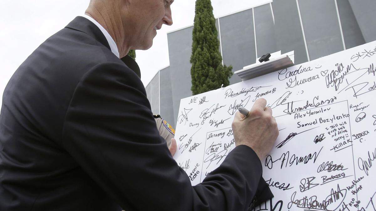 Gov. Rick Scott signs a pledge to not text and drive on a poster in front of the Alonzo and Tracy Mourning Senior High School in 2013 in North Miami. Scott spoke to students at the school before signing a statewide ban on texting while driving into law. The law makes reading or sending a text, emailing and instant messaging on smart phones while driving a secondary offense, meaning police have to first stop drivers for another offense like an illegal turn. WILFREDO LEE/AP File