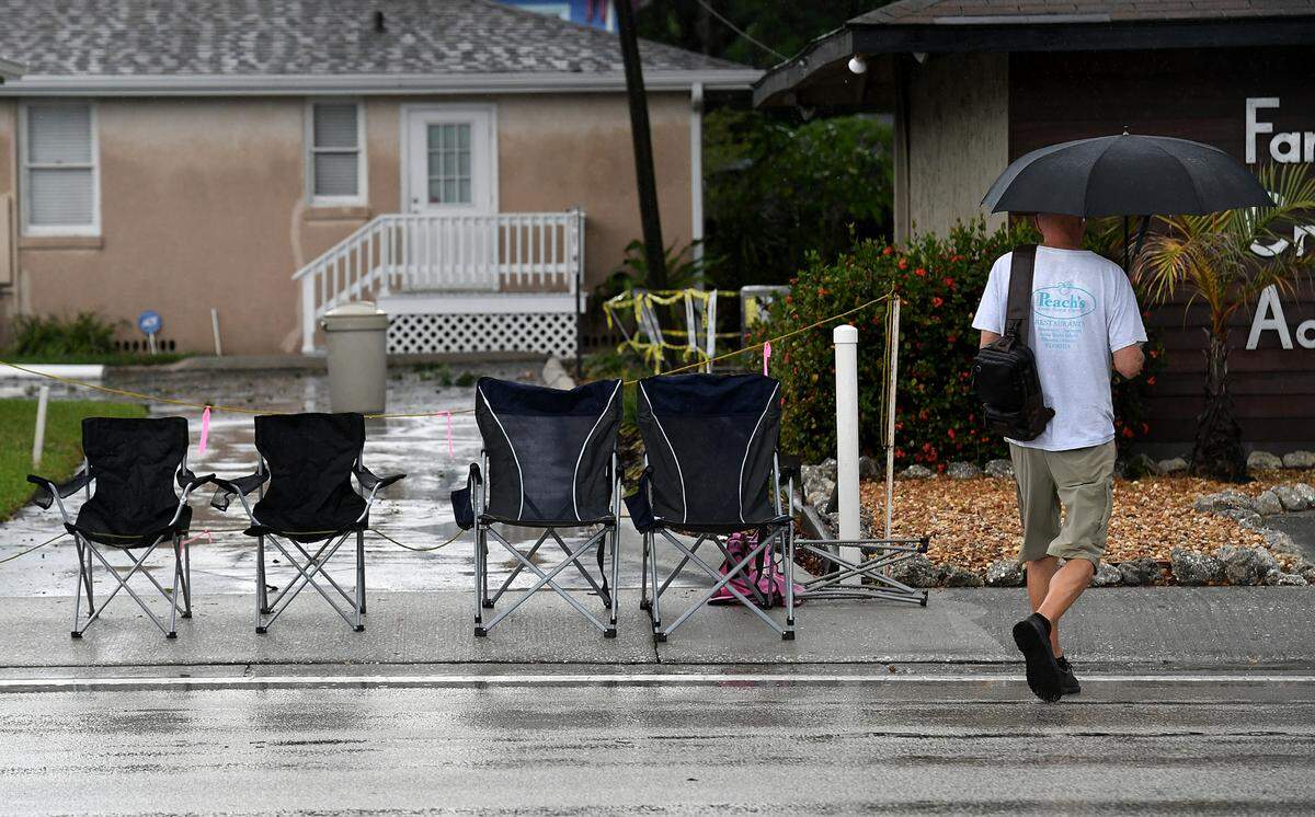 A man with an umbrella crosses Manatee Avenue after the 2022 De Soto Grand Parade was cancelled because of bad weather.