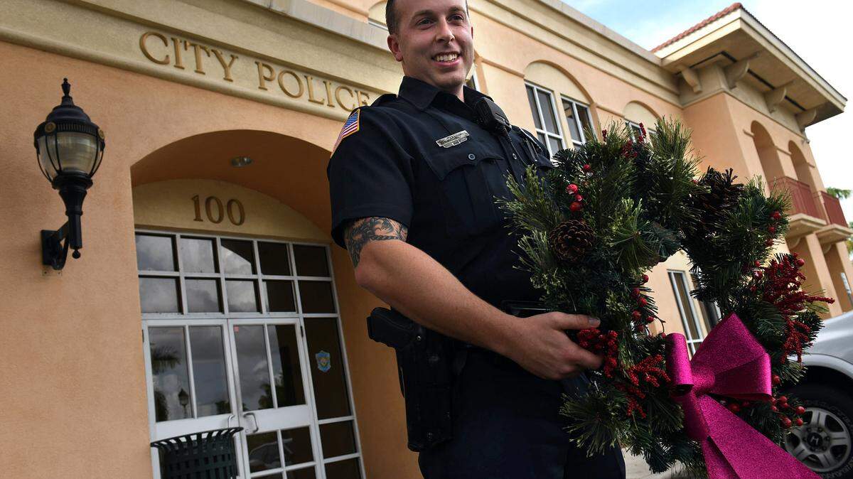 Bradenton Police officer Matthew Caradimos, holding a wreath from the department, helped a local couple whose holiday lights were stolen regain their Christmas spirit by replacing the lights with an inflatable Santa Claus. The thankful couple sent a letter of appreciation to Chief Michael Radzilowski. 
 TIFFANY TOMPKINS-CONDIE/Bradenton Herald