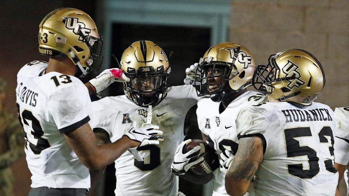 Central Florida’s Alex Swenson (30) is congratulated on his touchdown by teammates Dredrick Snelson (5), Bryon Brown (13) and Randy Shannon (53) during the second half of an NCAA college football game against host East Carolina on Saturday.