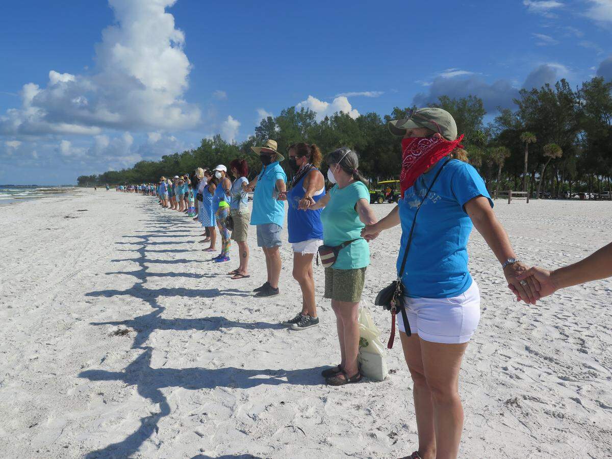 Hundreds of people gathered on Coquina Beach on Anna Maria Island Sunday morning as part of the statewide “Hands Along the Water.” The peaceful demonstration involves participants holding hands for 15 minutes along the water to bring awareness to the devastating red tide ravaging Florida’s beaches.