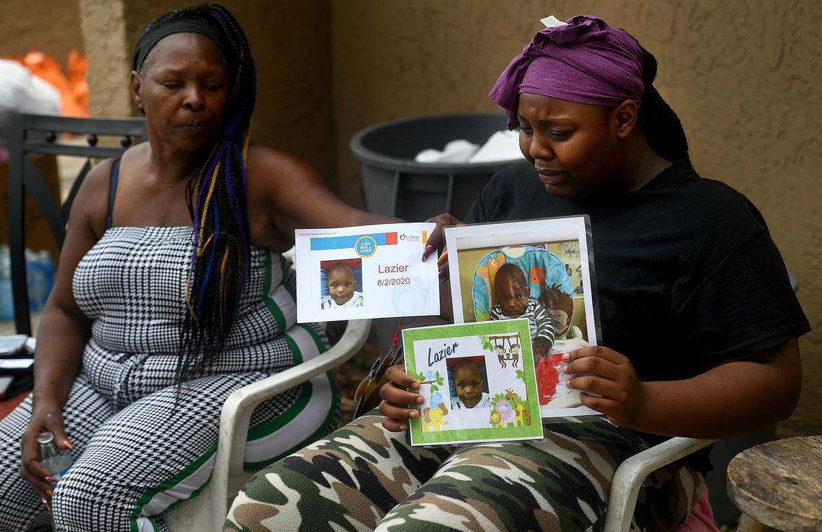 07/15/21—Debra Robinson sits with A’Nyjai Clarke as she cries softly and holds photos of Lazier, 11 months, who died in a fire in a quadplex in Bradenton early Thursday morning.