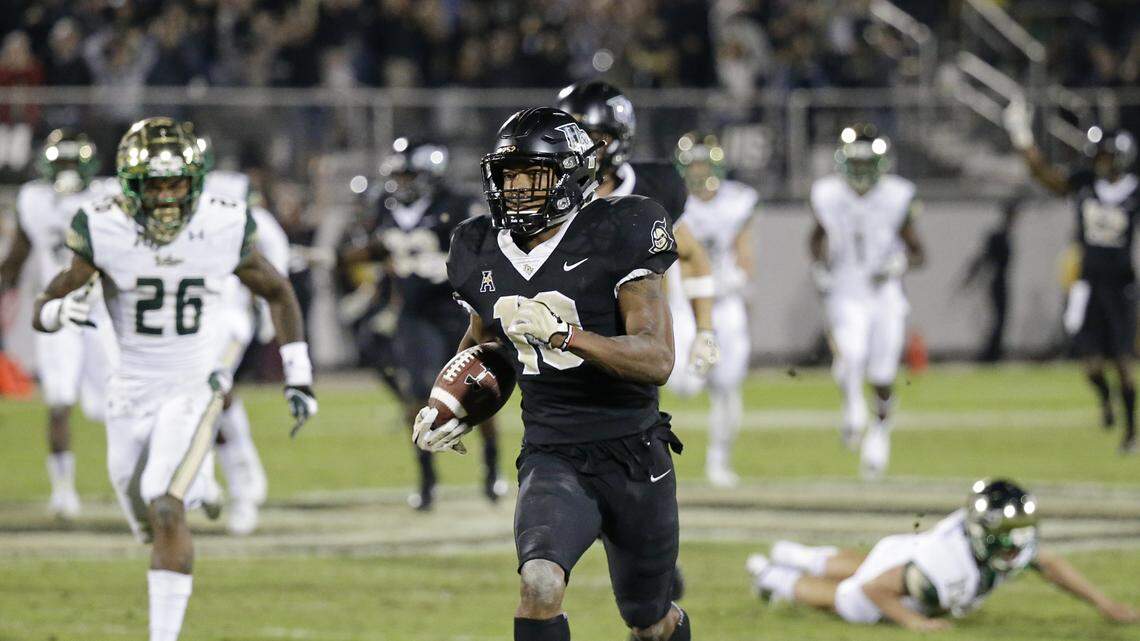 In this file photo, Central Florida's Mike Hughes returns a kickoff for a 95-yard game winning touchdown past South Florida defensive back Craig Watts (26) in the Knights' unbeaten season in 2017.