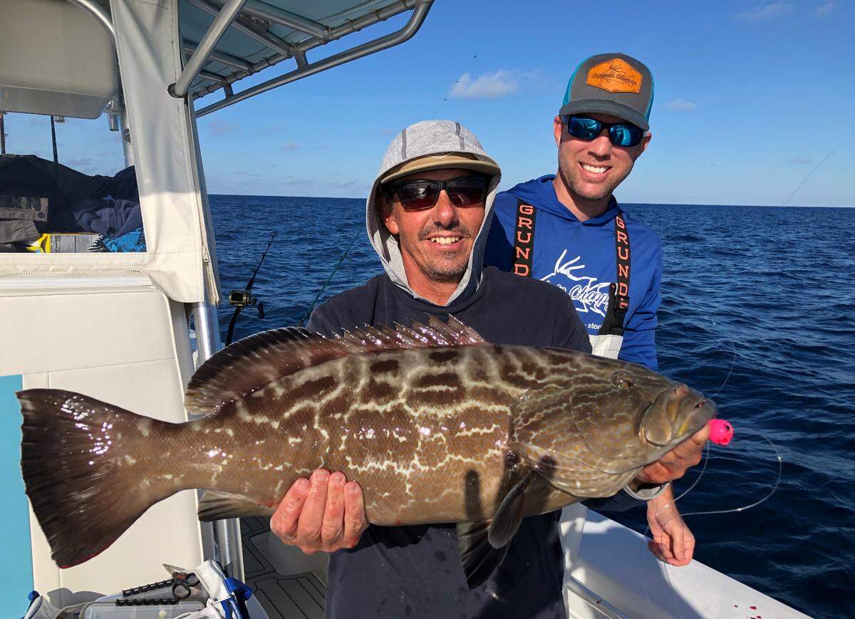 Tony Summers holds the black grouper he caught next to Jon Chapman.