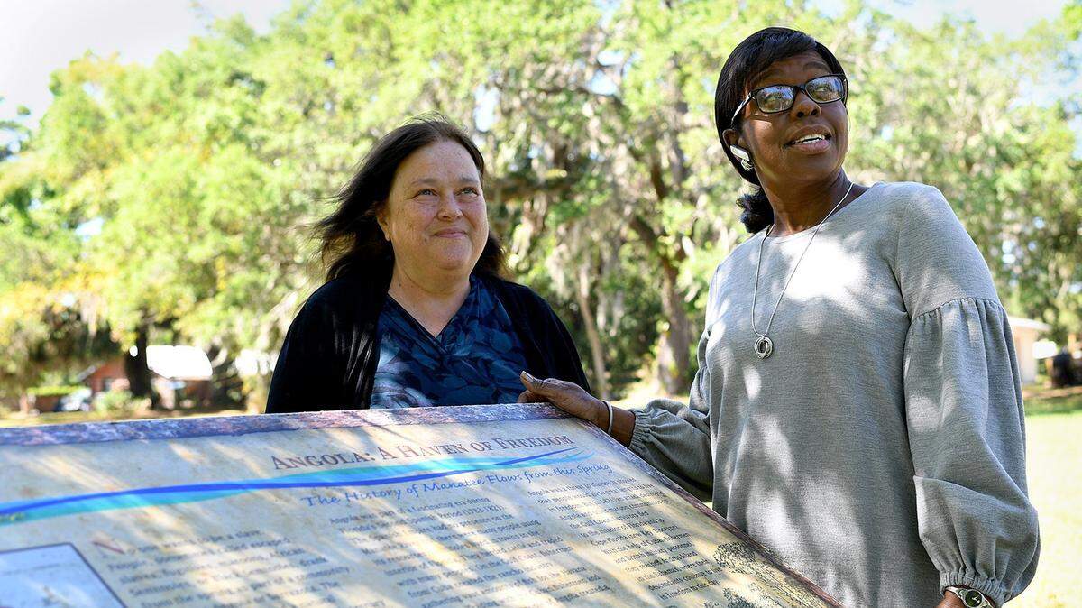 Trudy Williams of Reflections of Manatee stands with Daphney Towns, organizer of the Back to Angola Festival at Mineral Springs Park, which has revealed itself to be the location of New Angola, a settlement of escaped slaves who were driven out in 1821, escaping to the Bahamas. The pair will host the Back to Angola Festival from July 13-15.