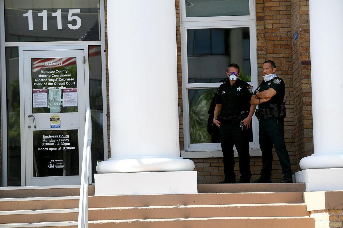 Two Manatee County deputies stand watch as State Rep. Anthony Sabatini lead an anti-mask rally with Rev. Joel Tillis at the Manatee County Courthouse Monday morning along with about 100 people.