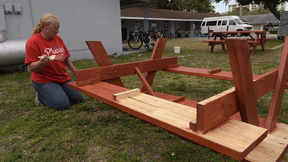 Connie Smith pauses as she stains one of two picnic tables donated to the residents of the Parkside Apartments in Bradenton. 
 TIFFANY TOMPKINS/Bradenton Herald