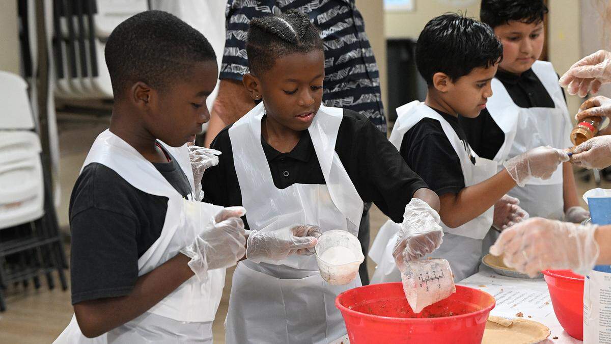 Students check a recipe while they make apple pies for their families’ Thanksgiving celebrations at Visible Men Academy on Friday, Nov. 17, 2023.