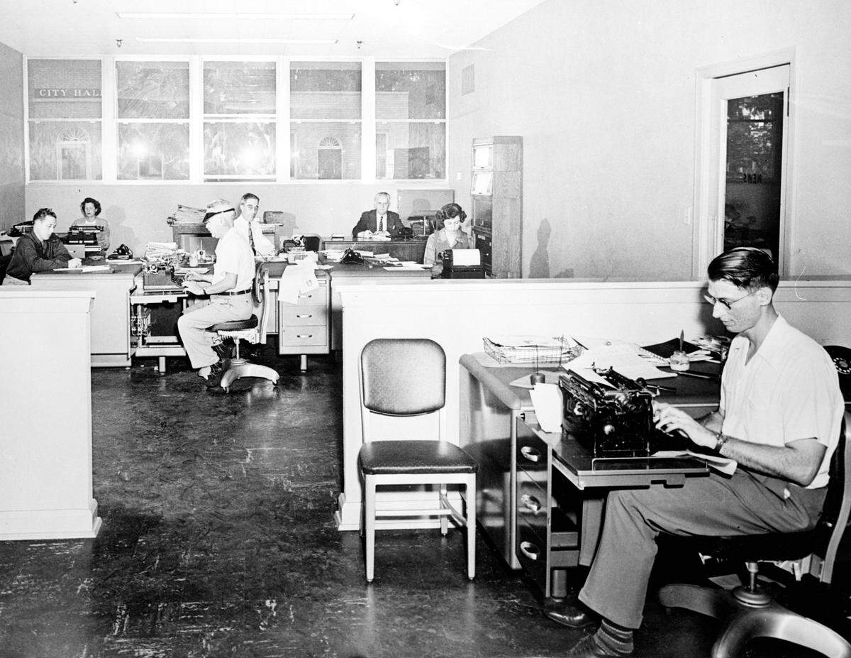 Bradenton Herald Newsroom. From left to right are John Douglas, society writer Polly Henry, wire editor Emory Smith, city and managing editor Brock Cheshire, editor Earl Eastwood, Barbara Stevens Ball and Ralph Warner. Taken sometime between 1940-49.