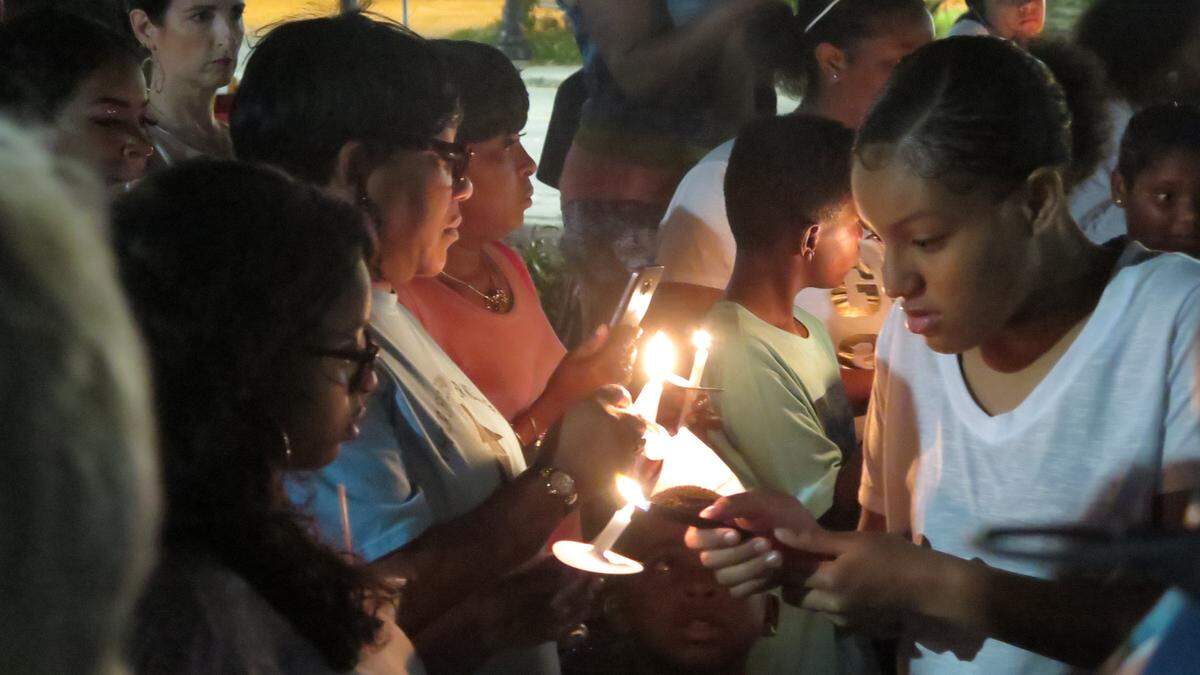 Guests light candles at a memorial service for Jabez Spann at Fredd Glossie Atkins Park in Sarasota on Saturday evening. About 200 people attended the event, holding candles and wearing white and gold to show honor Jabez’s life.