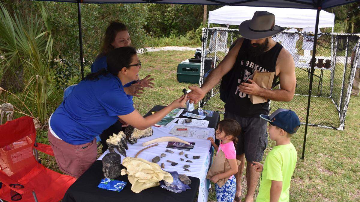 Representatives from the Bishop Museum of Science and Nature hand out shark teeth collected from Peace River to Shawn Silvious, and his children, Max and Tulip, at Manatee County’s 3rd annual World Oceans Day Festival at Emerson Point Preserve on Saturday morning.