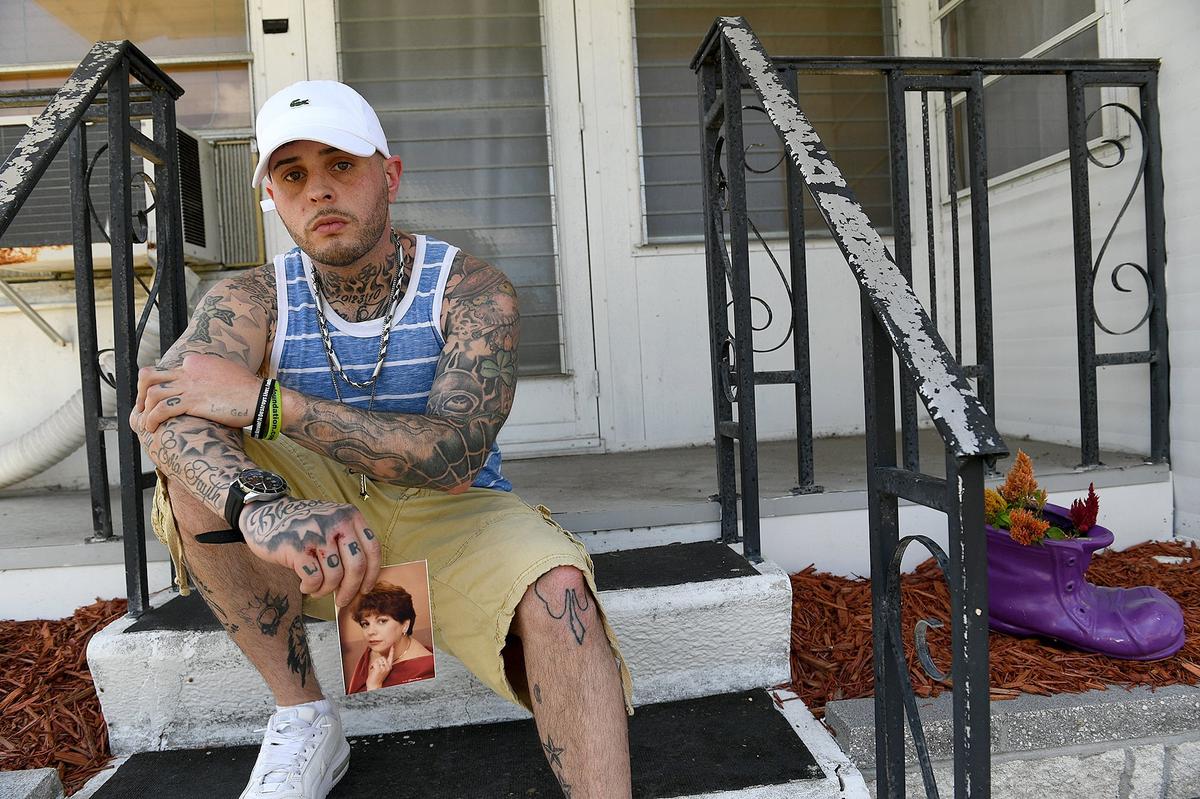 Robert Demeo holds a glamour photo of his mother, Joan Demeo, on the steps of the Royal Garden Estates mobile home where she lived and was killed April 18.