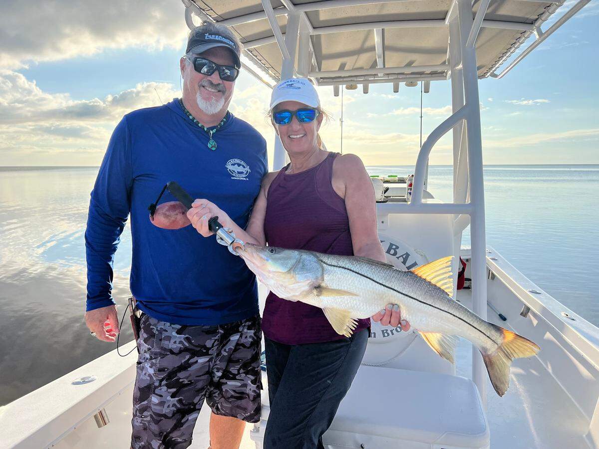 Captain Brock Wagner, 55, an Everglades charter fishing captain, poses for a photo with his wife Maureen Wagner holding a snook. The couple received unwarranted backlash after a different Captain Brock was caught on video confronting another boater.