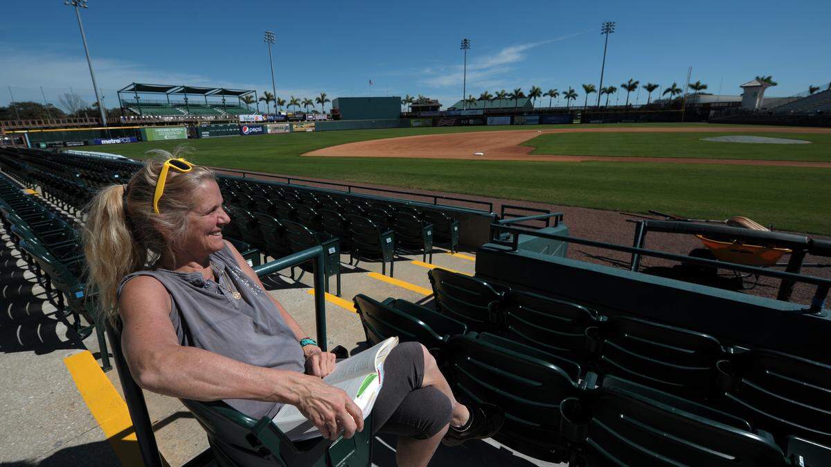 Wendy Peterson of Burlington, Mass., reads a book Wednesday at McKechnie Field as she waits for her sister to go through orientation to work at McKechnie during spring training. The Pittsburgh Pirates will have their first workout with pitchers and catchers Friday at Pirate City. The first home game is March 2 against the Detroit Tigers.GRANT JEFFERIES/Bradenton Herald