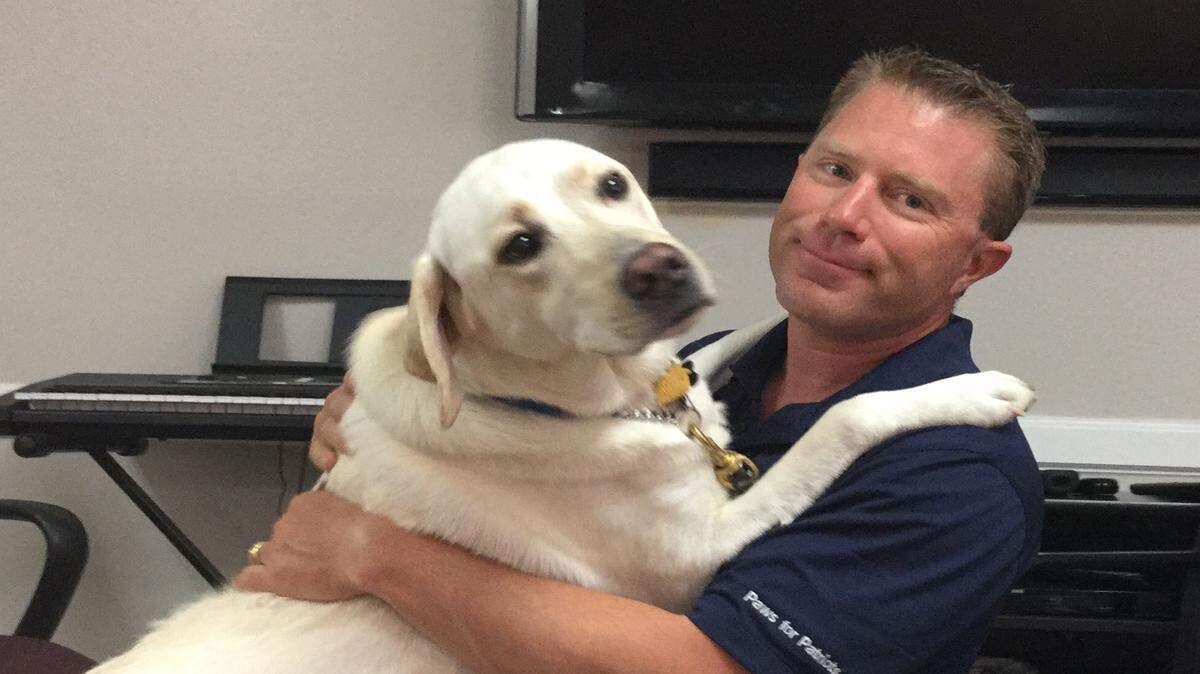 Air Force veteran Morgan Watt and his service dog Foley, a 2-year-old goldaore trained at Southeastern Guide Dogs Paws for Patriots program have a little fun during Foley's down time before Veterans Day. Foley is trained to detect Watt's service-related headaches and react to PTSD symptoms with what Watt called a deep 'spiritual love.' MARK YOUNG/Bradenton Herald