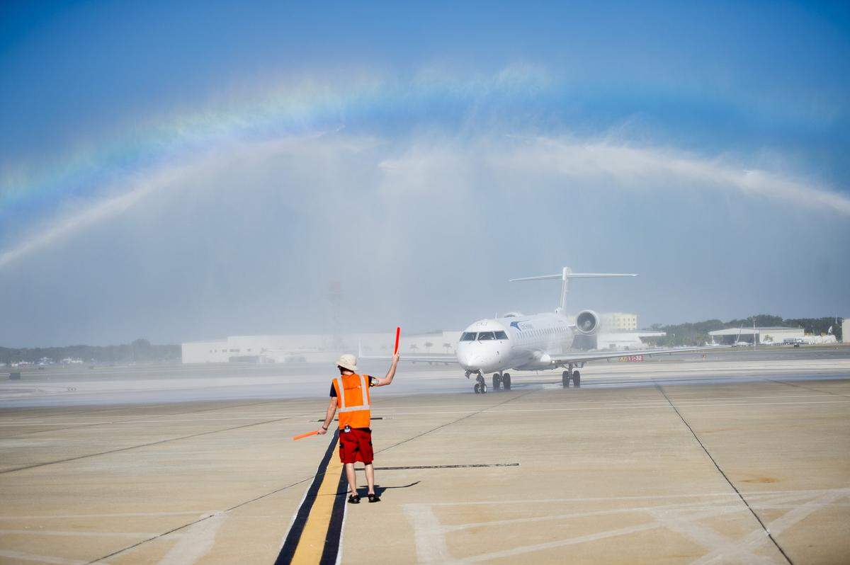 11/17/2016--An SRQ employee directs the first Elite Airways flight as it lands at SRQ Airport as firetrucks perform an aircraft water arch salute on Nov. 17, 2016, at Sarasota-Bradenton International Airport.