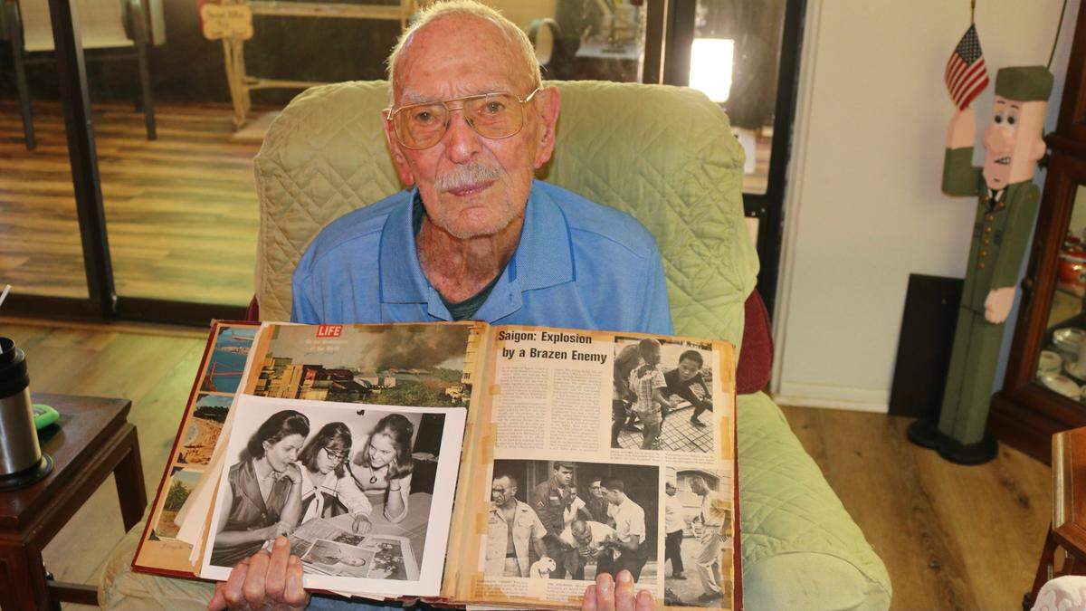 7/9/2021--Paut R. Atherton opens a family scrapbook that includes a Life magazine article and photo, at right, about the 1964 bombing of Brinks Hotel in Saigon by the Viet Cong. A photo at left shows his wife, Ginny, and daughters Nancy and Sandy looking at the article in 1965.