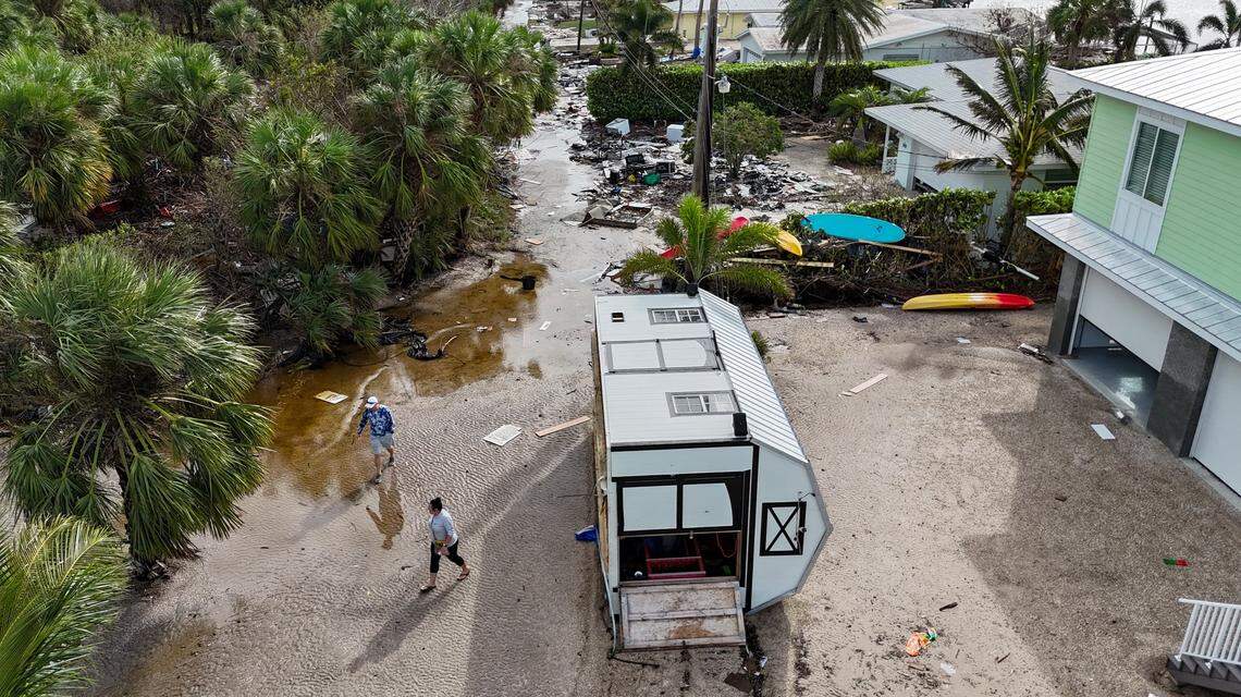 Karre Willis, right, and her husband walk through their neighborhood surveying damage and debris in front of their neighbors’ homes in Charlotte County near Manasota Key on Thursday, Oct. 10, 2024, the morning after Hurricane Milton hit the area.