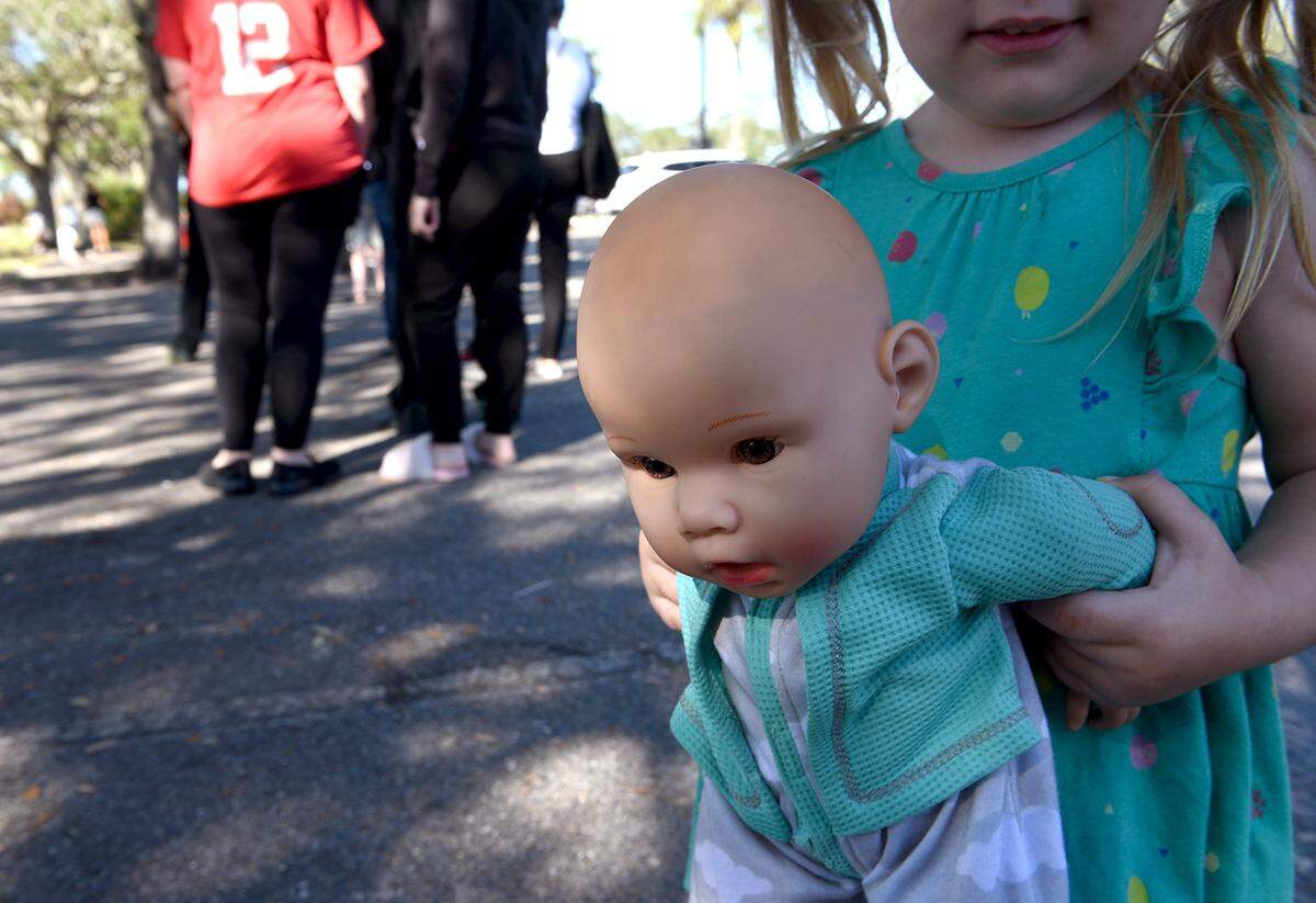 12/28/21—A small girl holds her doll as people form a long line at the Bradenton Area Convention Center in Palmetto where COVID-19 testing is ongoing. There were plans to move the site to a smaller location after the New Year, but the center will continue operating until further notice.