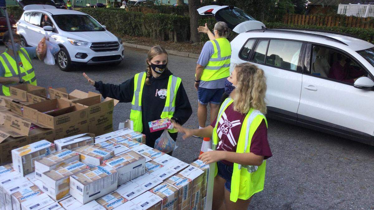 Volunteers at Saturday’s drive-thru food pantry at the Parrish United Methodist Church hand out crackers and other snacks at one of several food stops that served some 500 families with food, including everything a family needs for a Thanksgiving meal.