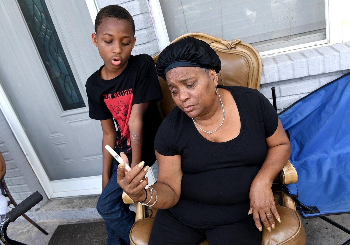 Denise Miller talks about her son, Jerome, who was killed Saturday when his vehicle, full of bullet holes, crashed into Rooms-To-Go. She sits with Jerome’s son, Jerome Jr., 12, as they watch Jerome sing on a YouTube video.