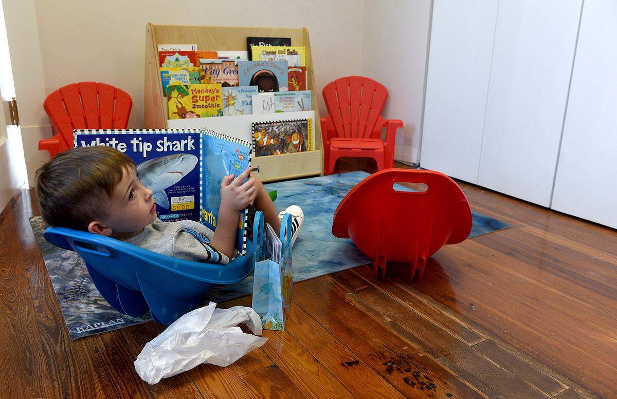 07/30/21—Lincoln Smith, 5, reads a book about sharks at the ribbon-cutting ceremony for the Forza Child Development Center at the Parrish Schoolhouse.