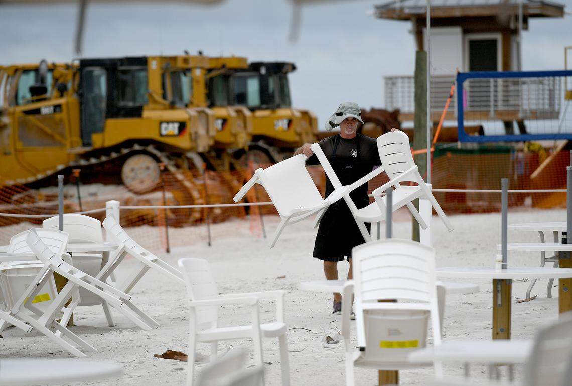 Pat O’Connor puts away tables and chairs at the Coquina Cafe. Tropical storm warnings have been canceled for the time being in Manatee County..