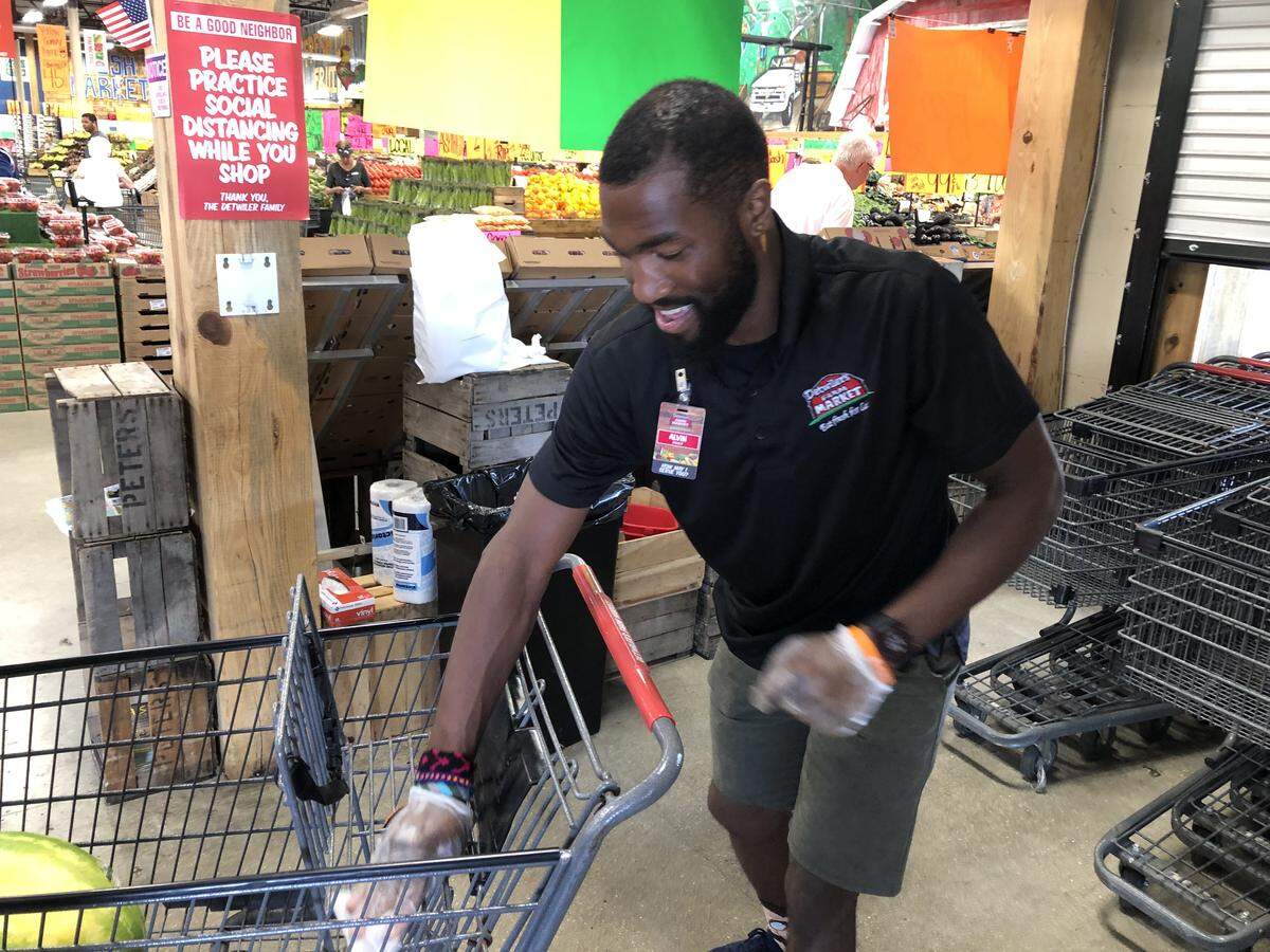 Alvin Ducre wipes down carts for customers at Detwiler’s Farm Market in Palmetto.
