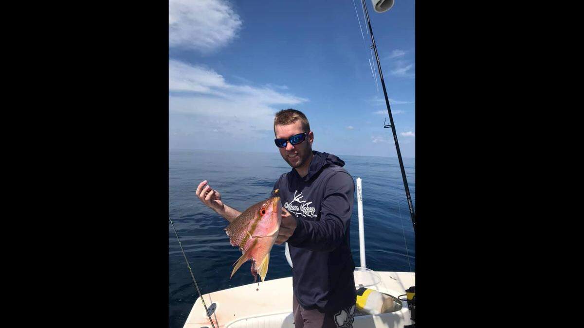 An angler poses with a yellowtail snapper that was killed before it could be reeled in due to shark depredation in the Gulf of America.