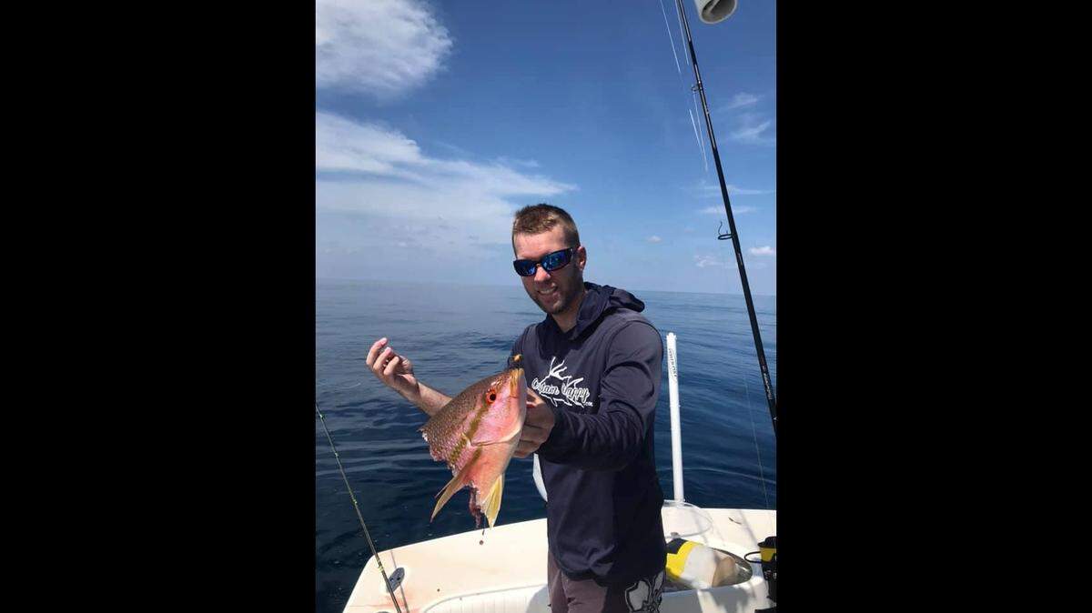 An angler poses with a yellowtail snapper that was killed before it could be reeled in due to shark depredation in the Gulf of America.