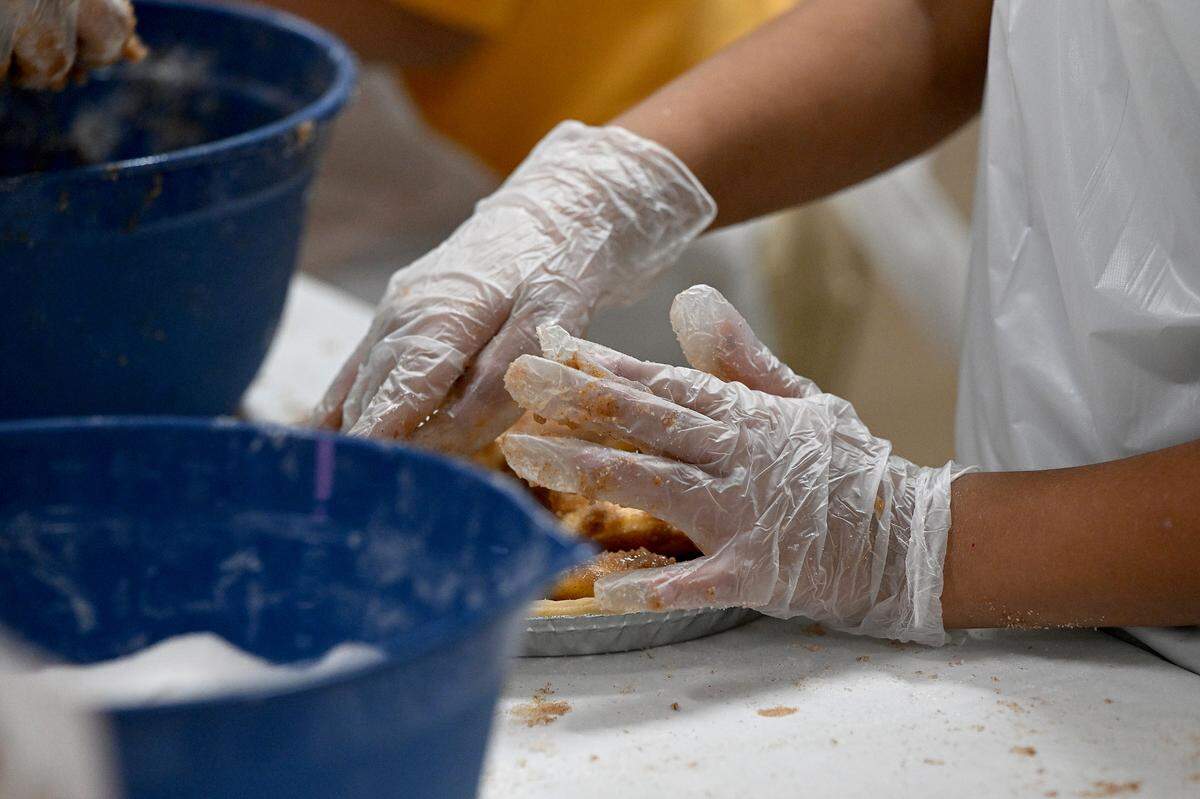 Students wear aprons and gloves while they make apple pies for their families’ Thanksgiving celebrations at Visible Men Academy on Friday, Nov. 17, 2023.