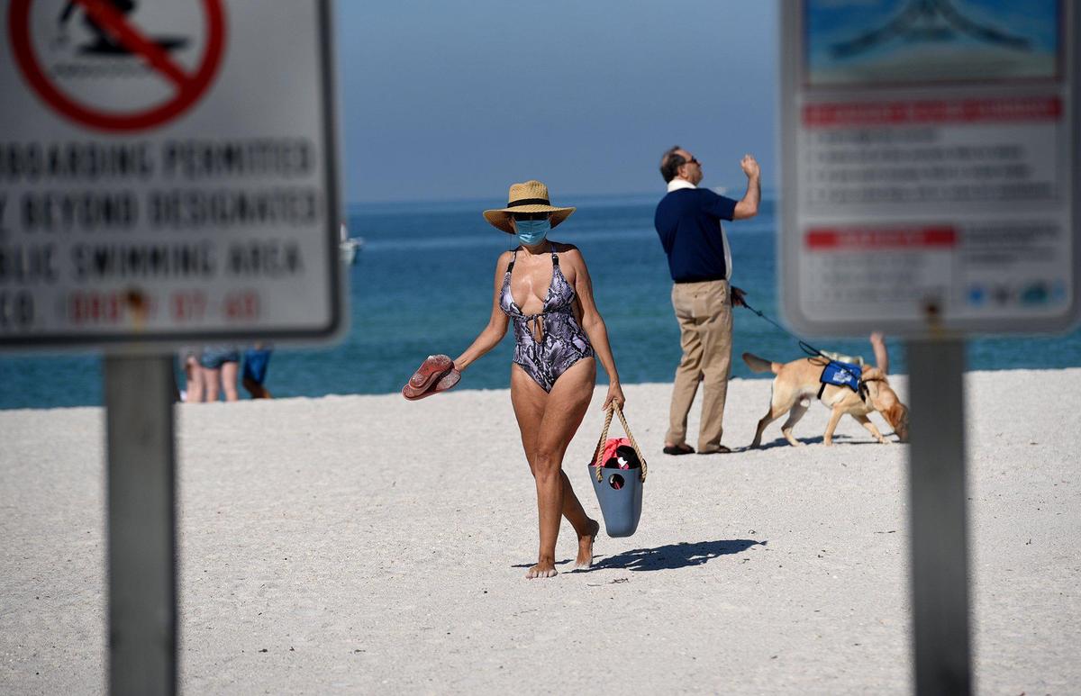 Early on the first day of the Manatee County public beaches reopening, blue skies and clear waters greeted the visitors. Rayna Piskova emerges from her long swim to put on a mask and make her way home.