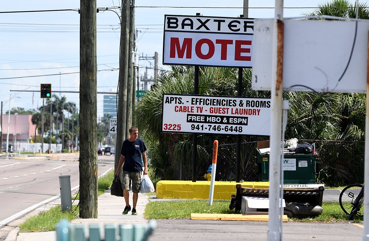 A pedestrian walks past the past hotels and small businesses on 14th Street West.