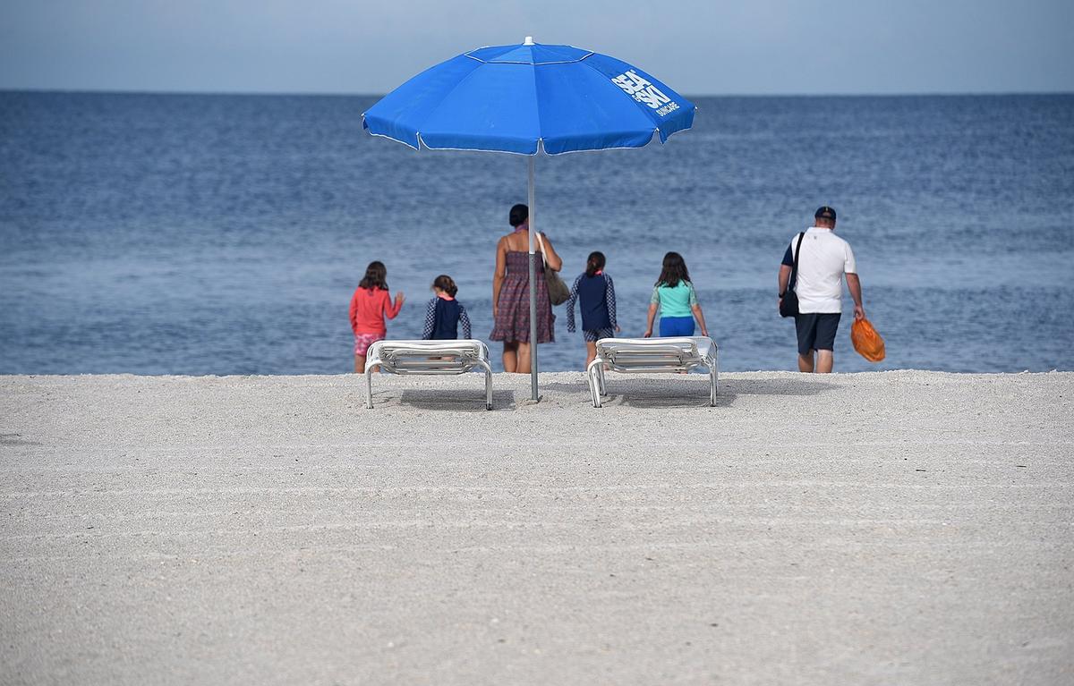 Red tide has hit area businesses hard, keeping crowds away from the island. But owners have hopes that Labor Day weekend business will be strong. A family makes their way cautiously to the water’s edge on Manatee Public Beach Thursday.