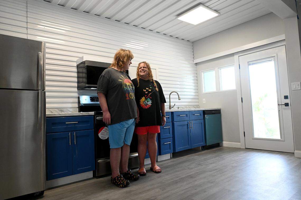 Dustin Muir and his mother, Denise Jones, stand in the main room of their new tiny house build from shipping containers by Glen Gibellina. The cabinets and other details were painted a special blue in memory of Denise’s mother’s favorite “Blue suede” of Elvis fame.