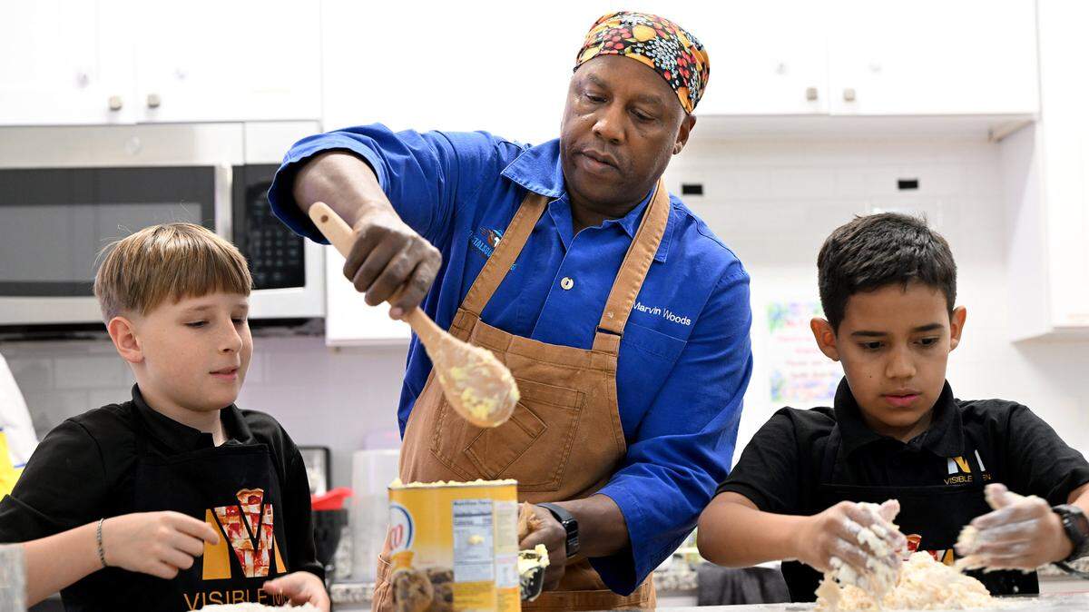 Wyatt Morton and Melkis Ruiz, 5th-grade students at Visible Men Academy, learn how to make apple pies for Thanksgiving from celebrity chef Marvin Woods.
